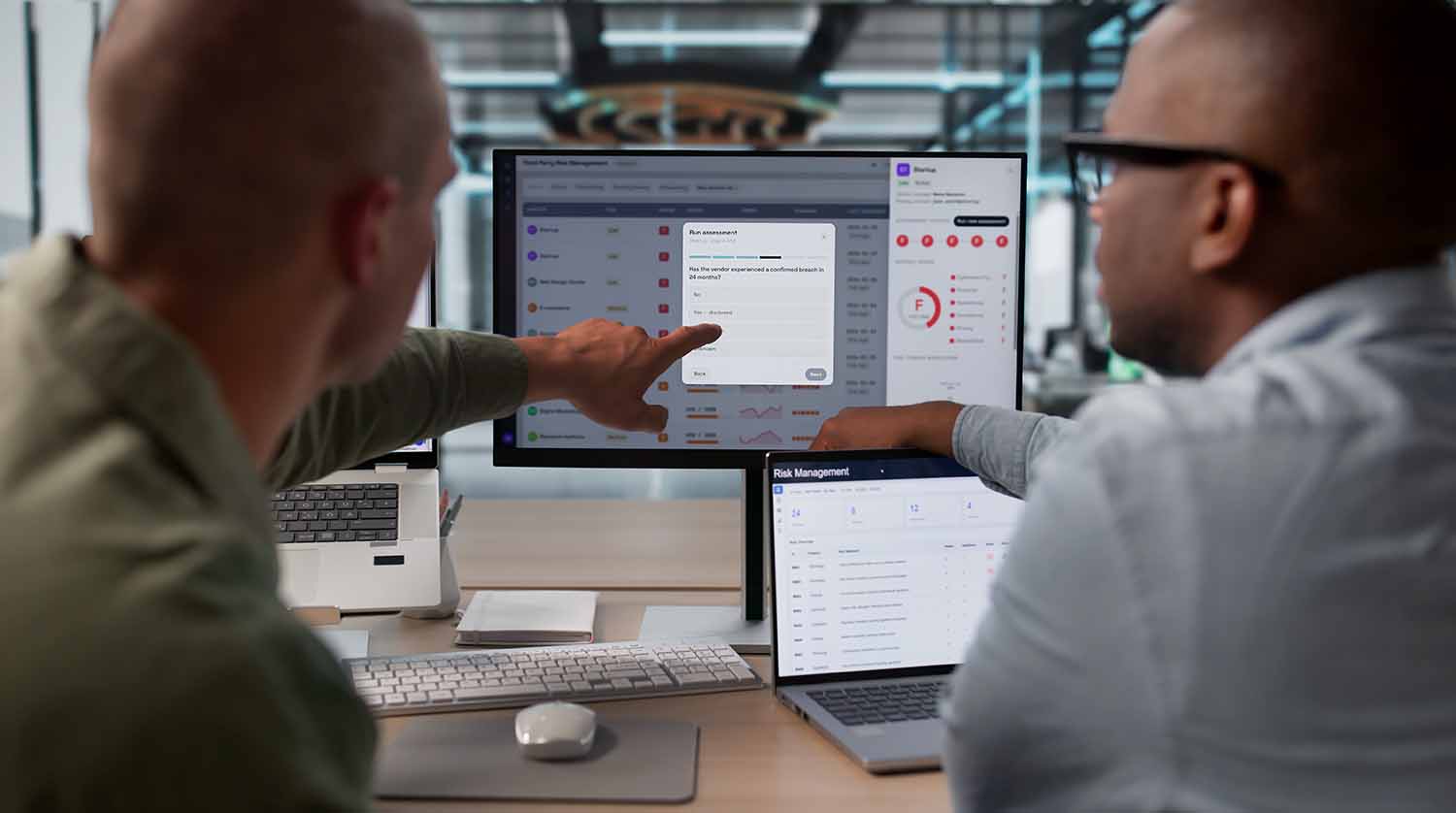 Two colleagues undertaking cyber review at their desks.